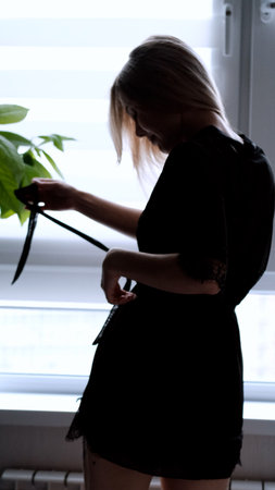 A woman in a black negligee stands near the window in the bedroom.の写真素材