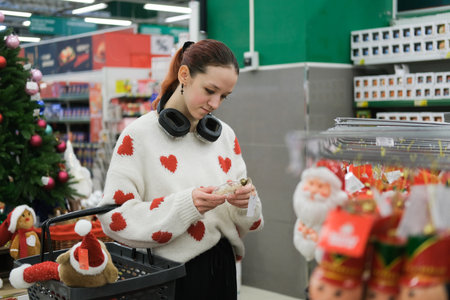 A store sells Christmas decorations. A young girl is choosing decorations for the Christmas...