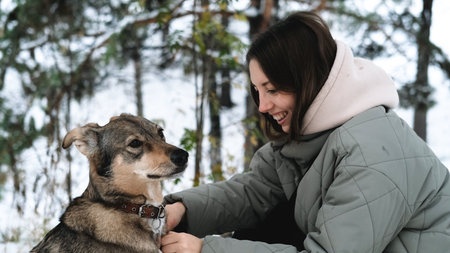 A young woman walks through a winter pine forest with her dog
