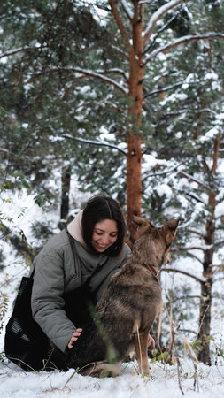 A young woman walks through a winter pine forest with her dog