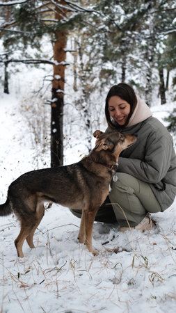 A young woman walks through a winter pine forest with her dog