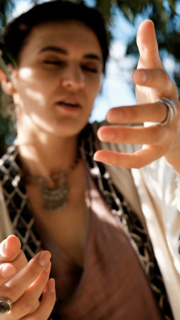 A beautiful brunette dressed in boho style meditates and dances in the forest. A magical ritual takes place against a green forest backdrop.の写真素材