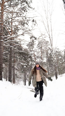 A young woman relaxes during a walk in a winter forest with her dog.の写真素材