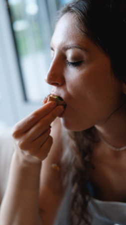 A beautiful girl eats food with her hands with gusto in a restaurant