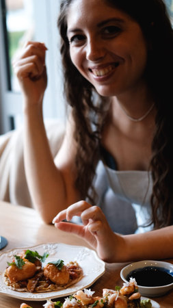 A beautiful girl eats food with her hands with gusto in a restaurant