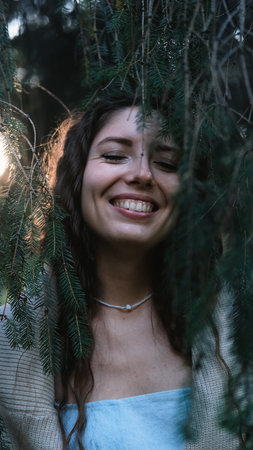 Portrait of a very beautiful young woman in a summer spruce forest at sunset.