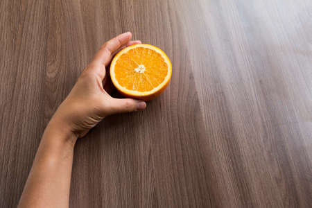 woman's hand holding a half of an orange fruitの写真素材