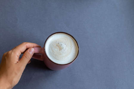 hand holding cup of coffee on wooden background