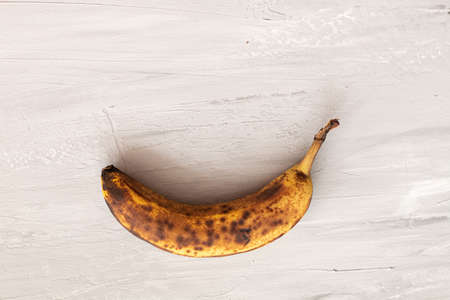 spoiled tainted bananas on gray background. Ugly food trendy photo. Food waste, food garbageの写真素材