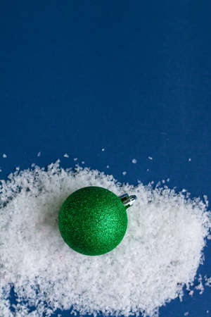 Green bright shiny Christmas ball isolated on snow, template with space for textの写真素材