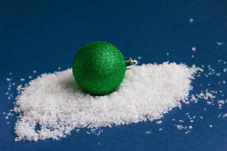 Green bright shiny Christmas ball isolated on snow, template with space for textの写真素材