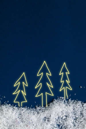 Christmas fir glowing silhouette with snow, blue background, empty space for textの写真素材
