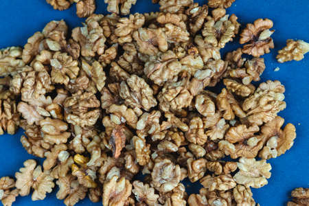 Walnut seeds texture top view on blue color background, empty space for text, organic healthy food...