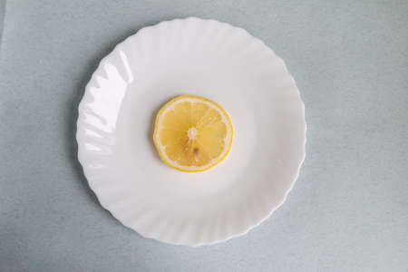 lemon slice on a white plate, light blue backgroundの写真素材