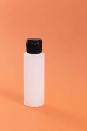 Plastic empty bottle for hygiene or cosmetics products, orange background