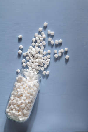marshmallows in a glass jar on light blue background
