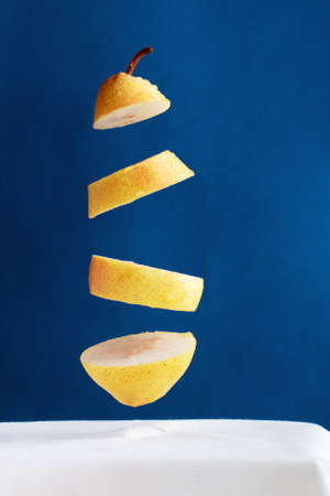 floating pieces of yellow pear against blue background, creative picture