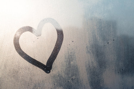 hand drawing heart on frozen window with natural sunlightの写真素材