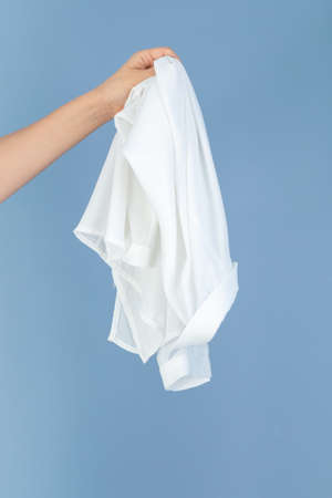 hand holding a white silk textile, blue background empty space for text