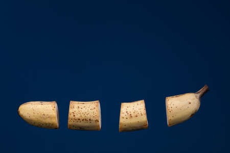 floating pieces of yellow overripe banana against blue background, creative picture