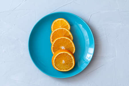 slices of orange on a blue plate, flat lay view, gray backgroundの写真素材