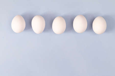 group of white chicken eggs on light blue background, empty space for textの写真素材