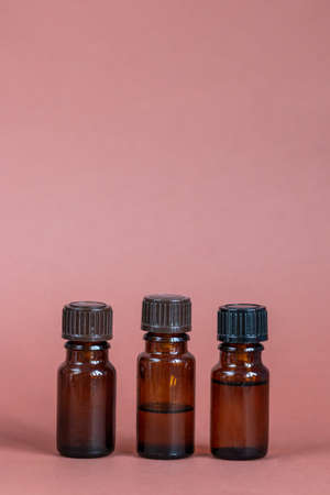 three glass container of essential oil on brown backgroundの写真素材