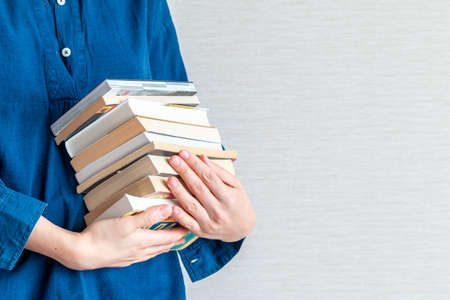 woman is holding a lot of books in hand, empty space for textの写真素材