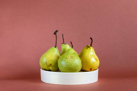 green fresh pears on white podium against brown backgroundの写真素材