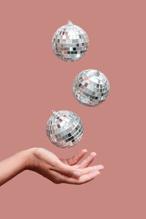 disco ball floating in the air under hand against beige backgroundの写真素材