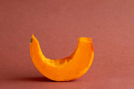 Slices of orange pumpkin on brown background, empty space for textの写真素材
