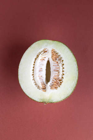 Half of green melon on brown background top view