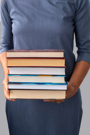 woman is holding stack of books