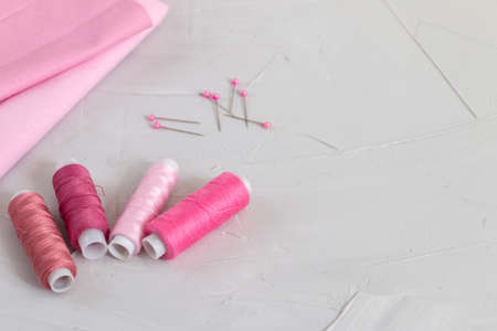 Thread and cotton fabric in pink color against gray background, slow fashion and home sewing conceptの写真素材