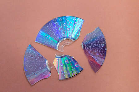 broken retro CD disc with wet drops against brown backgroundの写真素材