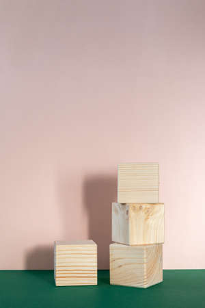 wooden cubes still life against pale pink and emerald green background