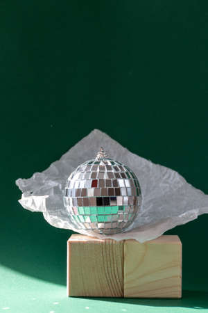 Still life with wooden cubes and disco ball reflecting sun flares against emerald green backgroundの写真素材