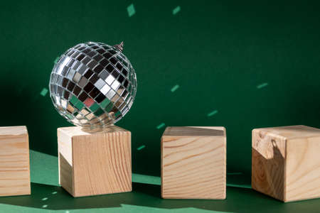 Still life with wooden cubes and disco ball reflecting sun flares against emerald green backgroundの写真素材