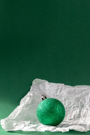 Green Christmas ball in torn paper against emerald green backgroundの写真素材