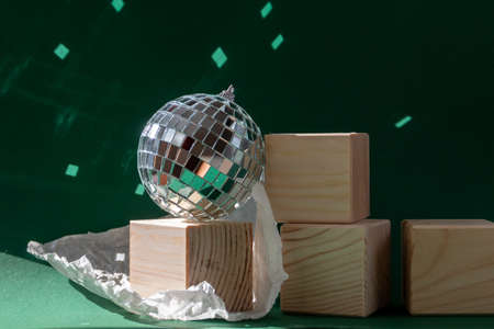 Still life with wooden cubes and disco ball reflecting sun flares against emerald green backgroundの写真素材