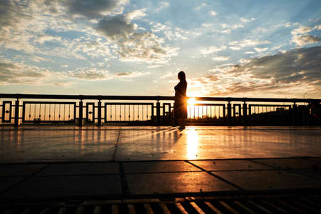 sunset on the pier with woman silhouette