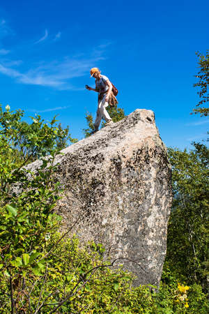 Woman on the big stone during hiking in the forest.の写真素材