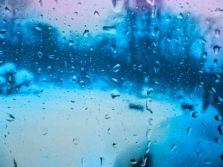 Drops of rain on the glass and blurred winter landscape outside the window in the morningの写真素材