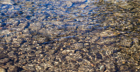 Shining ripples on the surface of transparent clear water of river for natural background.