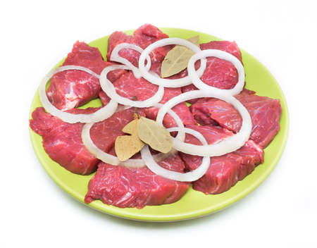 Appetizing pieces of beef with onion and bay leaf on green plate on white background.の写真素材