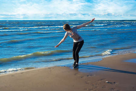 Happy young woman standing on the beach. She feels freedom and happiness.の写真素材