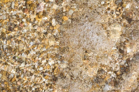 Beautiful background with water, pebble, liquid ripples and bubbles on the surface of the sea.の写真素材