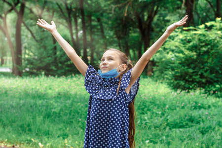 Quarantine is over concept. Little girl taking off mask outdoor and smiles.の写真素材