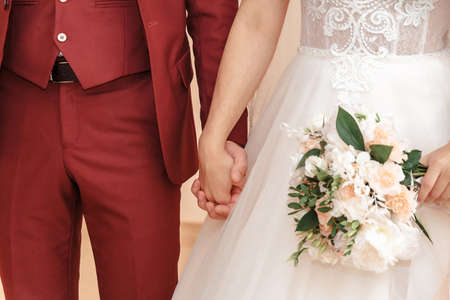 Young married couple holding hands, ceremony wedding day.