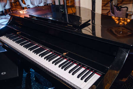 Close-up of a black piano in a restaurant with black and white piano keys.の写真素材
